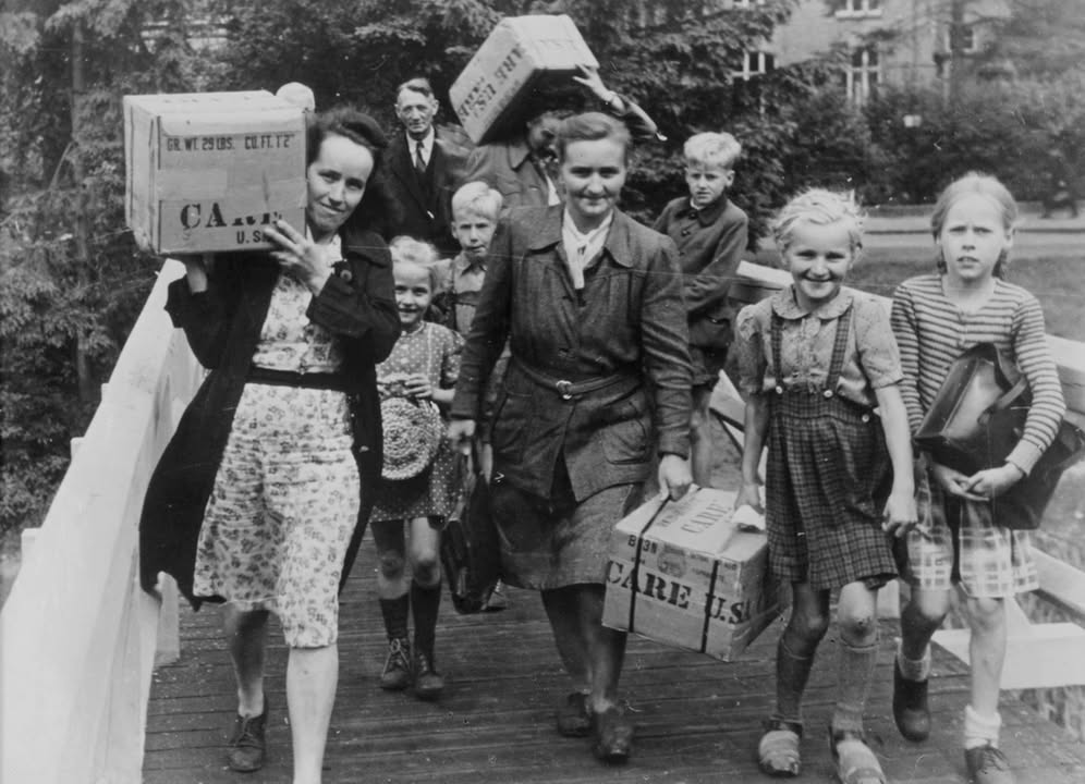 Dankbare Mütter, Männer und glückliche Kinder schleppen CARE-Pakete nach Hause. Foto: CARE Deutschland/Care.de