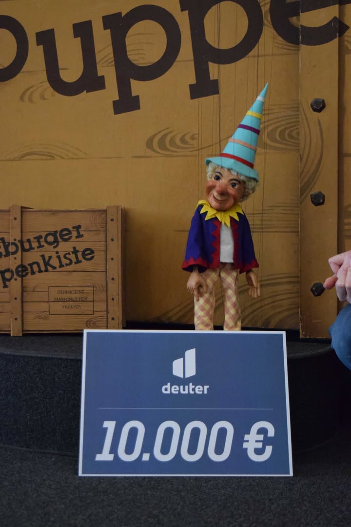 Heut‘ ist ein besonderer Freudentag … scheint der Kasperl von der Augsburger Puppenkiste zu sagen und bedankt sich bei der Gersthofener Firma deuter und den deuter-Kunden!